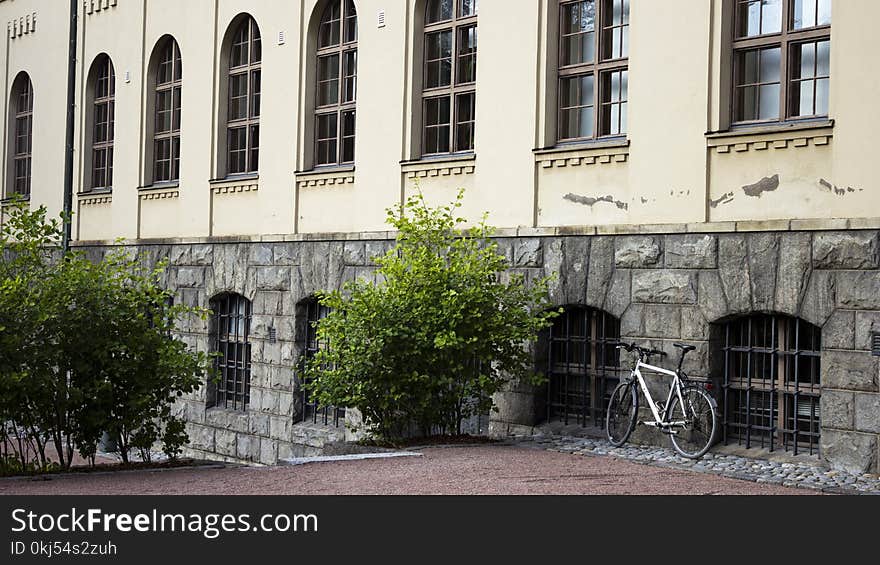 White Bicycle Parked Beside Gray Building