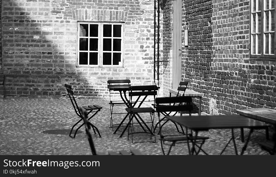 Grayscale Photo of 4-piece Dining Set Near Concrete Building