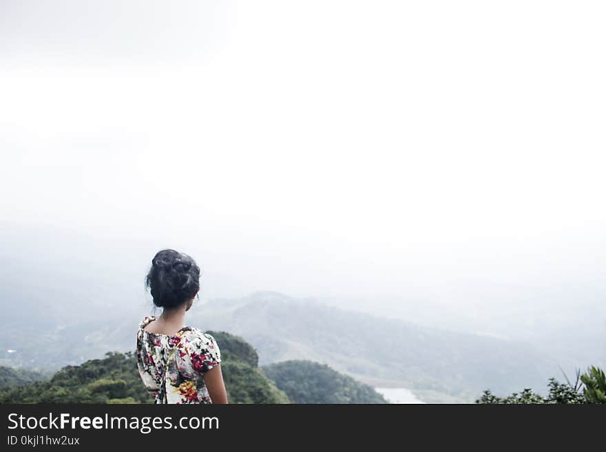 Woman Wearing Multicolored Floral Top Standing Near Mountain Under White Sky