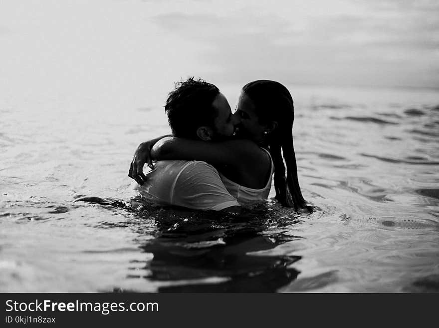 Man and Woman Kissing Together on Body of Water