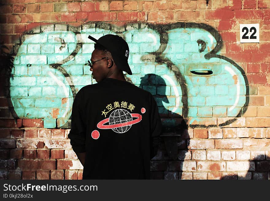 Man Wearing Black Long-sleeved Shirt Stands Near Red Wall