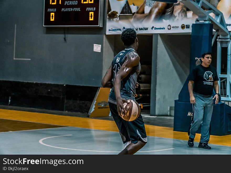 Man Holding Basketball on Blue Floor