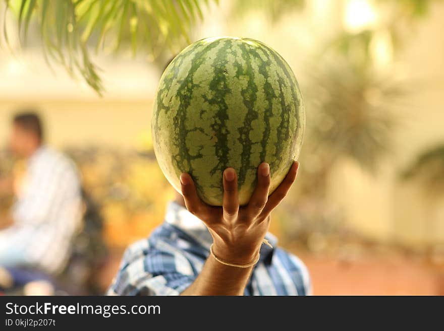 Selective Focus Photo of Man Raising the Watermelon