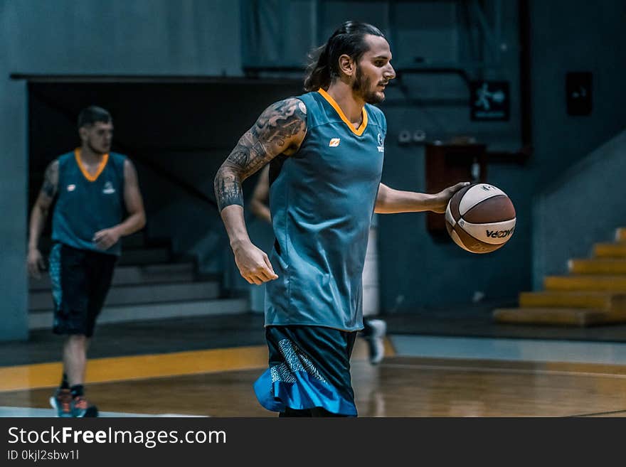 Man Holding Brown and White Basketball