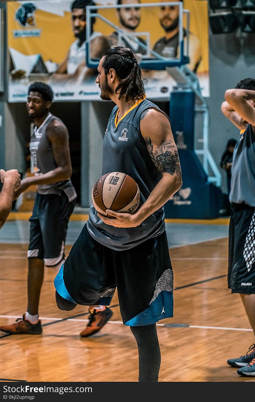 Man in Gray Sleeveless Shirt Carrying White and Brown Spalding Basketball