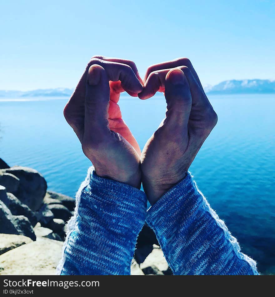 Person With Folded Hands Near Body of Water