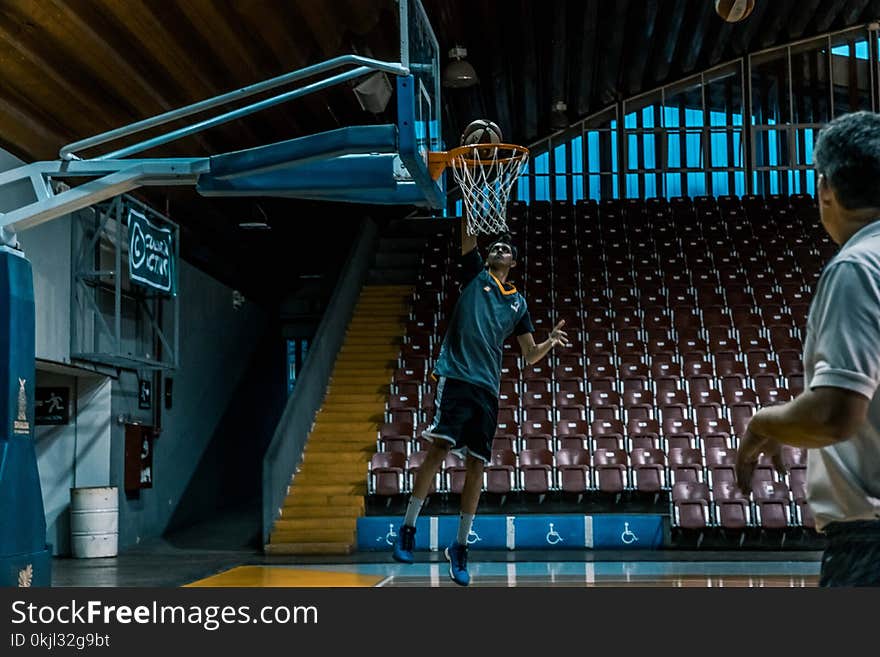 Man in Blue Shirt Trying to Dunk in Basketball Ring