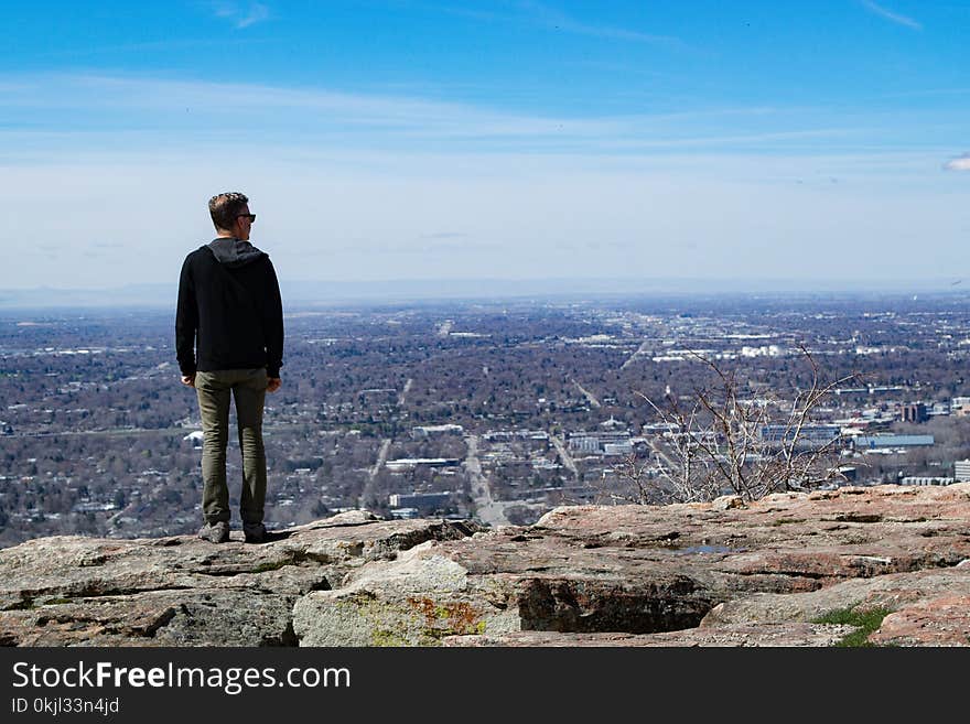 Man Wearing Black Jacket Standing on Rock Monolith