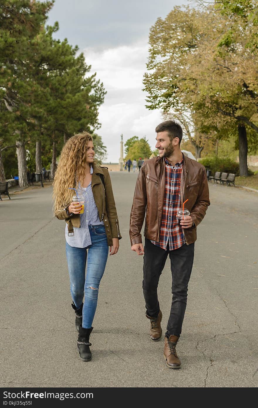 Man and Woman Wearing Brown Coats Walking on Pavement