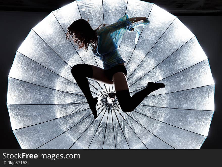 Jumping artistic woman in black underwear over flashing photo umbrella. Jumping artistic woman in black underwear over flashing photo umbrella.