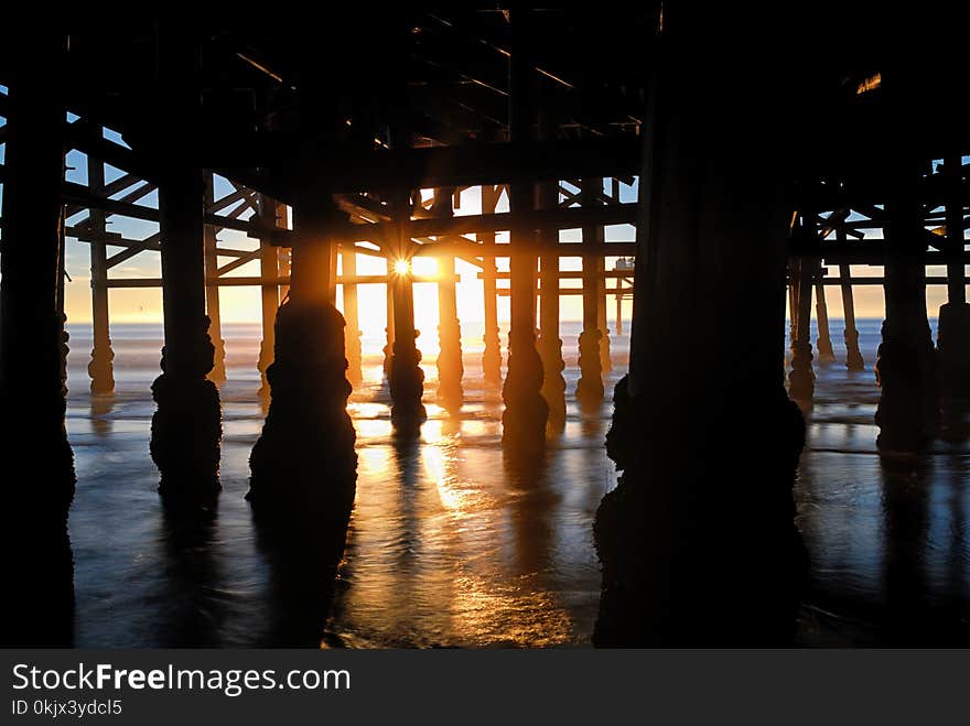 Dark silhouettes of the multitude of structural members an supports of this beach marine structure. Dark silhouettes of the multitude of structural members an supports of this beach marine structure.