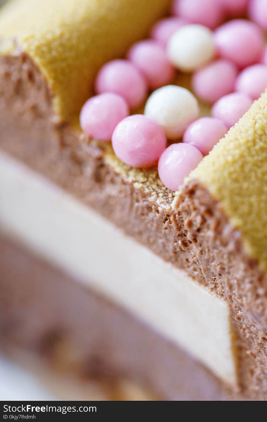 Luxurious dessert with pink chocolate spheres. Yellow mousse birthday cake with multicoloured sweet sugar balls. cut, chocolate coffee filling. Luxurious dessert with pink chocolate spheres. Yellow mousse birthday cake with multicoloured sweet sugar balls. cut, chocolate coffee filling