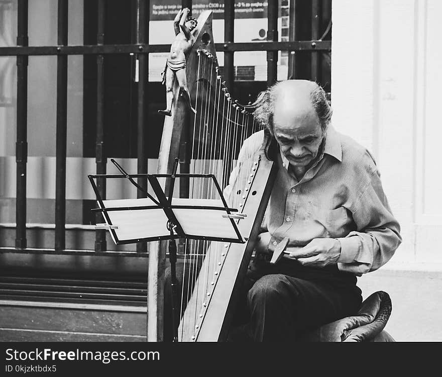 Greyscale Photo of Man Holding Harp