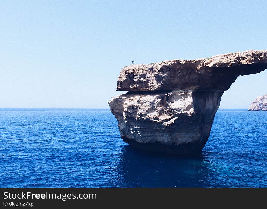 Person Standing on Rock Formation Cliff