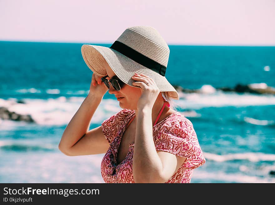 Selective Focus Photo of Woman Wears Beige Sun Hat Stand Behind Body of Water a Daytime