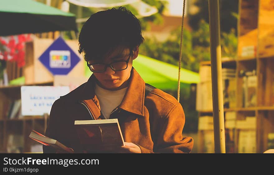 Man in Brown Jacket Holding a Book