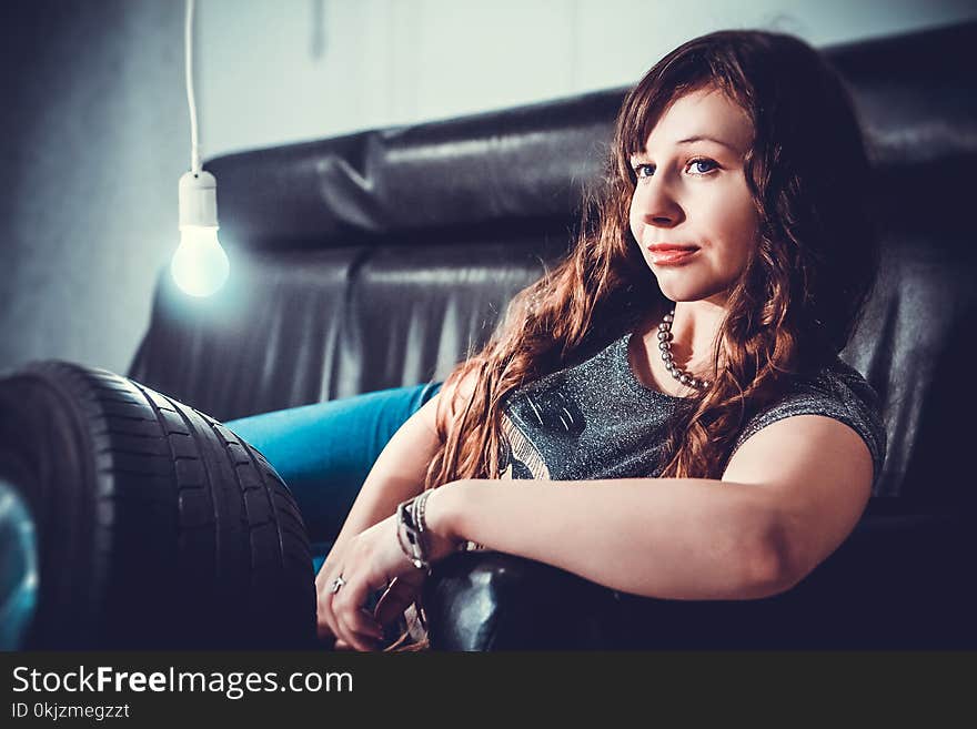 Woman in Gray Shirt Lying on Black Seat Sofa With Bulb Beside