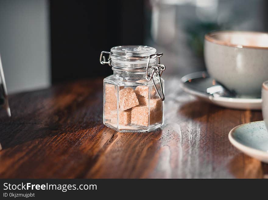 Clear Condiment Shaker With Brown Sugar Cubes Near Gray Teacup