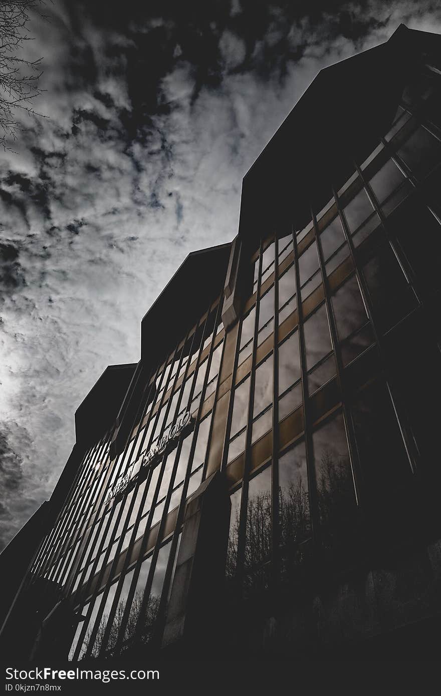 Brown Concrete Building With Glass Window Under Gray Sky