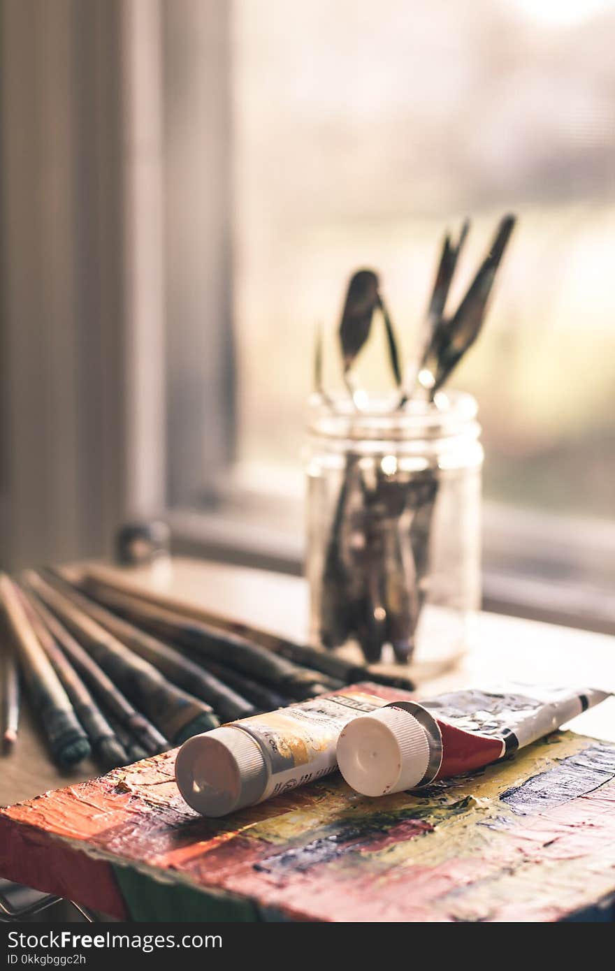 Shallow Focus Photography of Two Ink Tube Bottles Near Glass Jar