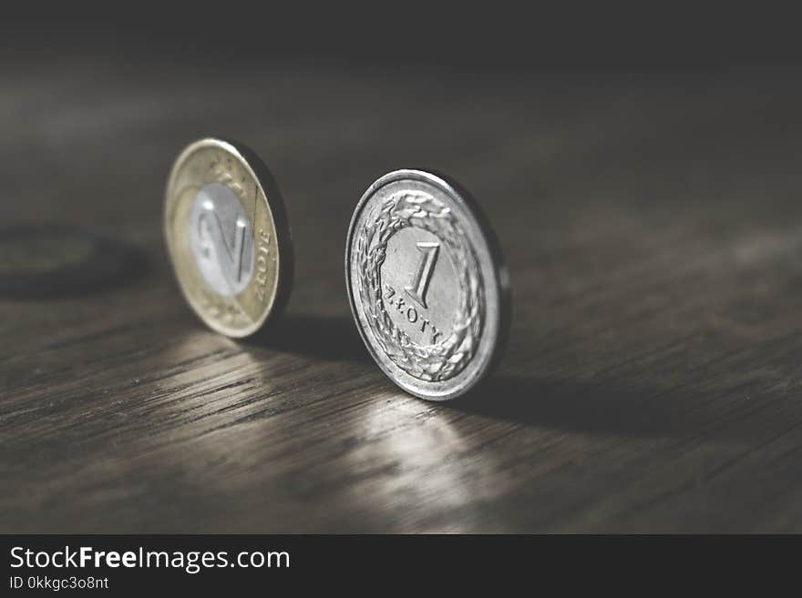 Photo of Two Gold-colored and Silver-colored Coins Standing on Floor