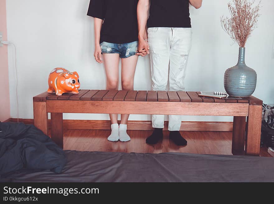 Woman and Man Holding Hand Standing Near Brown Coffee Table Inside Room