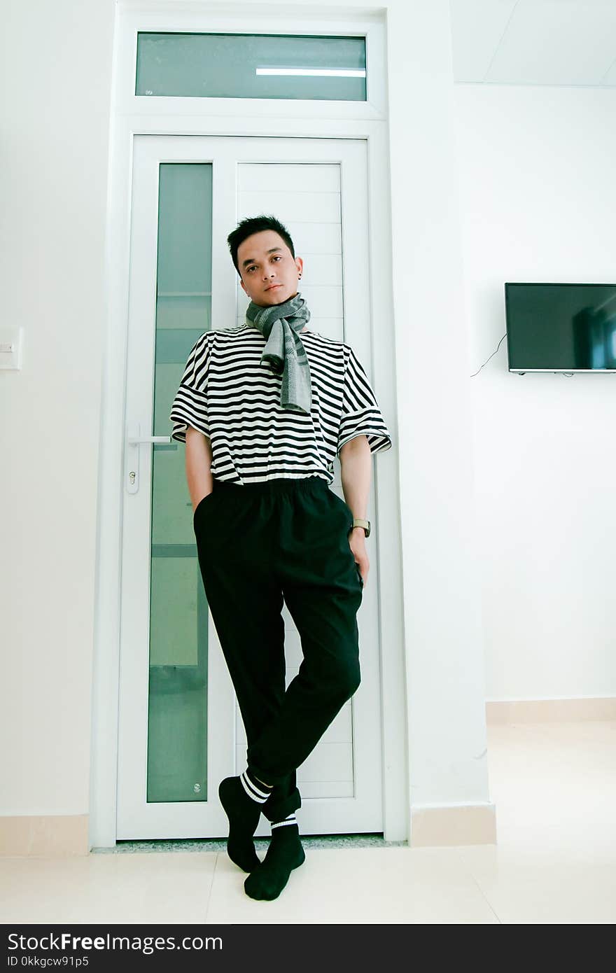 Man in Black and White Striped Shirt Leaning on Door