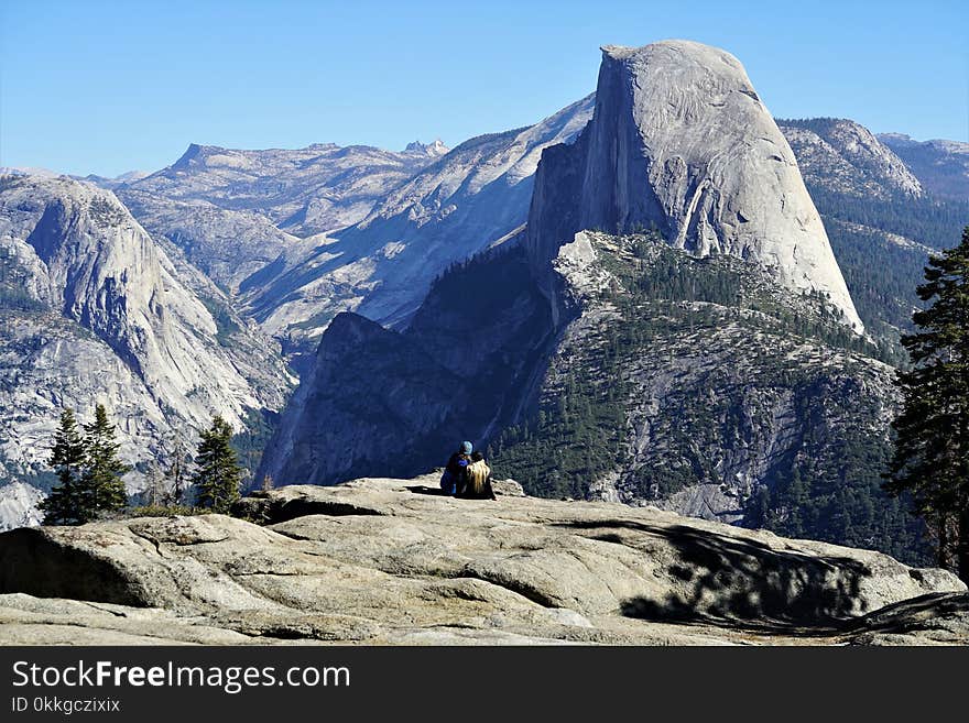 Two People Sitting on Mountain Edge