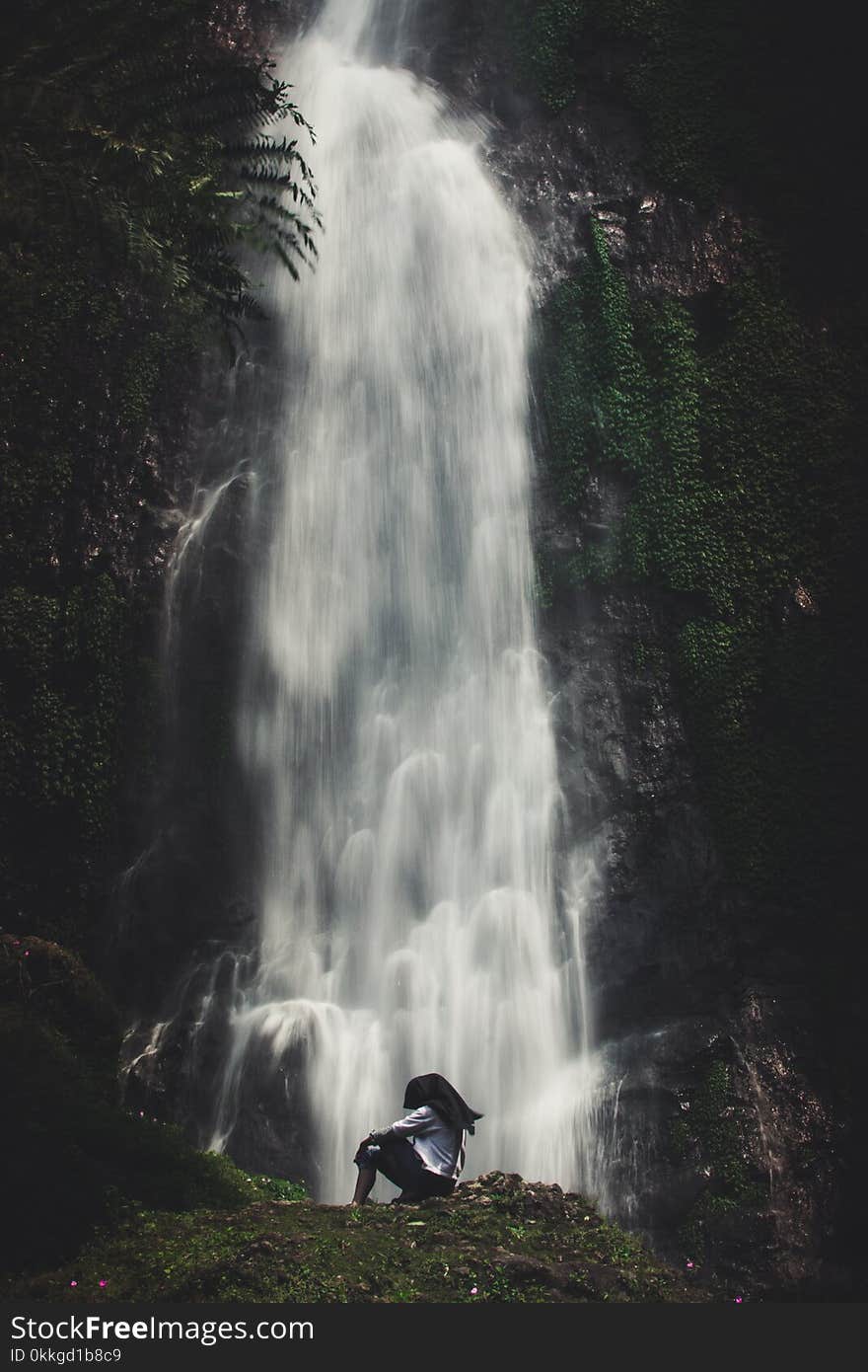 Photo of Man Sitting Near Waterfalls