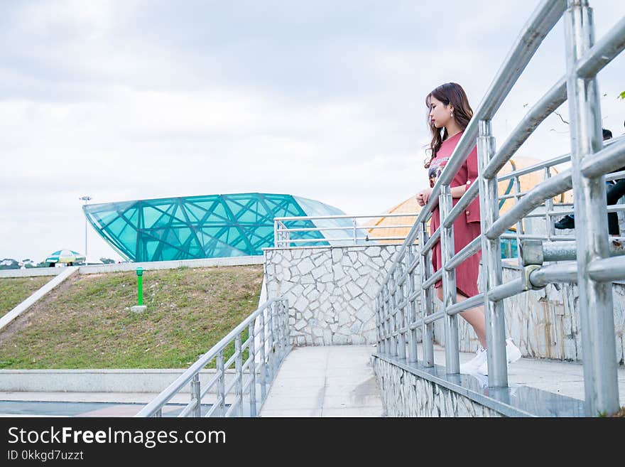 Woman Wearing Red Crew-neck Dress Near Gray Wall