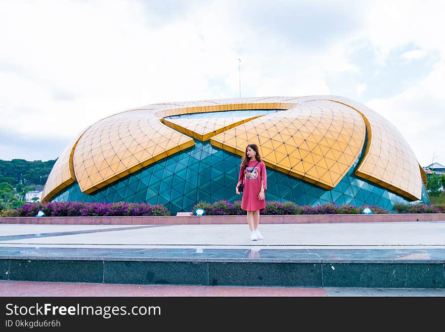 Woman Standing Near Blue and Yellow Dome Under White Cloudy Skies at Daytime