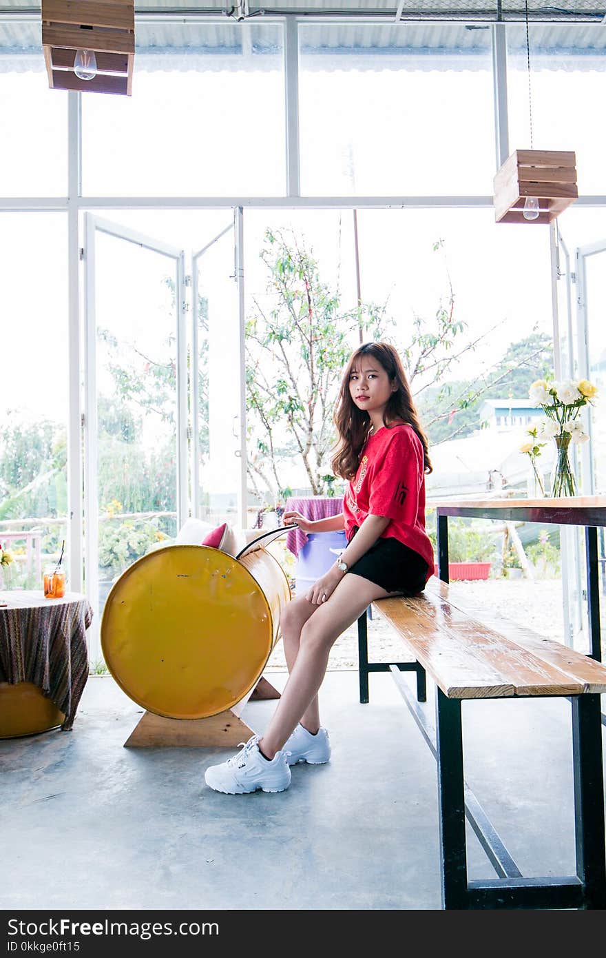 Woman Wearing Red Crew-neck T-shirt Sitting on Bench