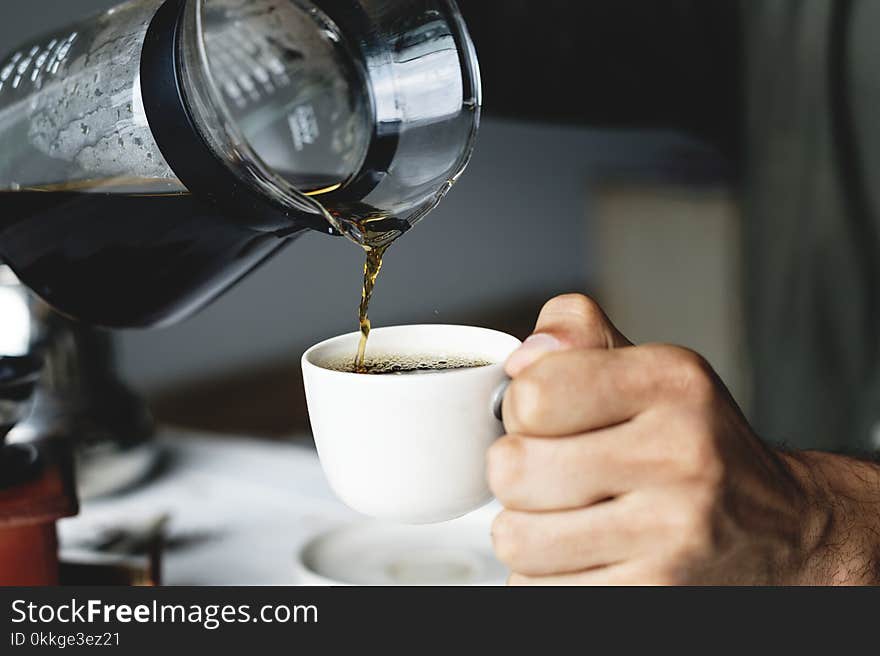 Person Holding White Ceramic Cup and Glass Pitcher