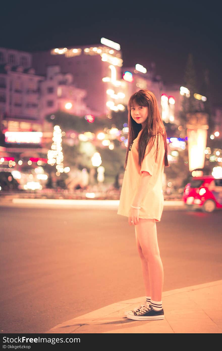 Woman in White Shirt Standing on Roadside during Night Time