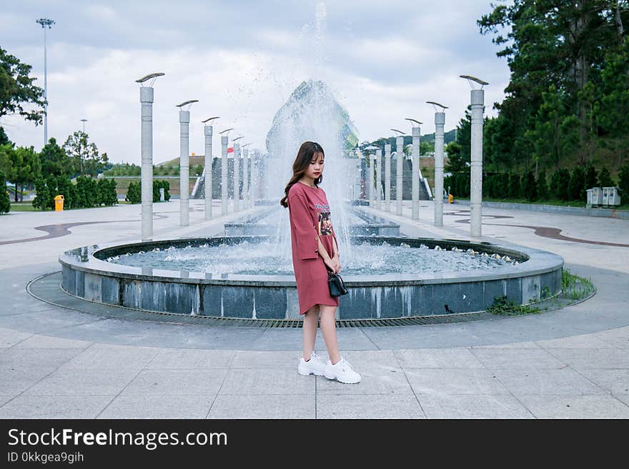 Woman Wearing Pink Crew-neck Long-sleeved Midi Dress Standing Concrete Outdoor Fountain