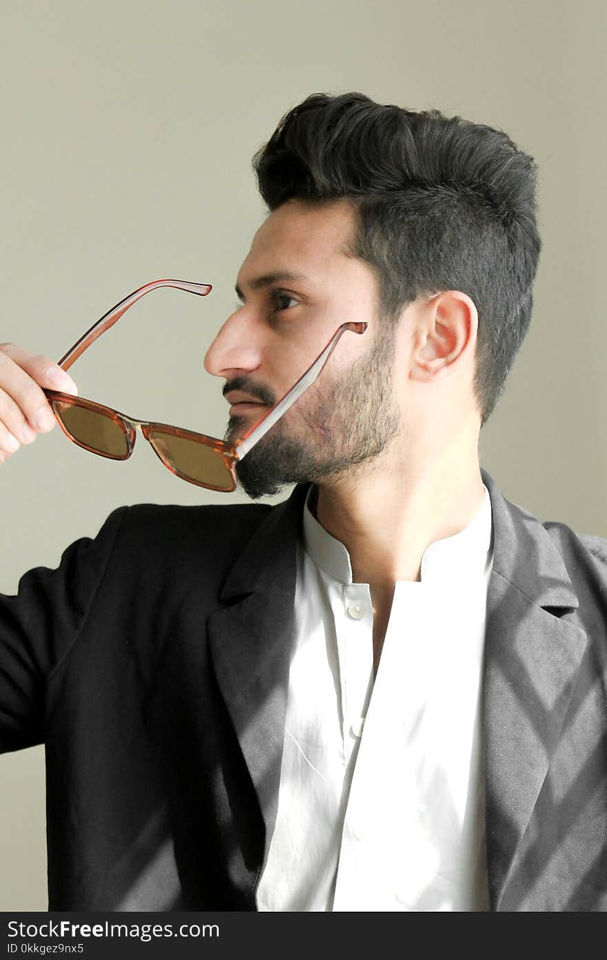 Man Holding Brown Framed Sunglasses With Black Suit