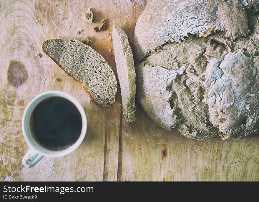 Loaf of homemade freshly baked bread and cup of coffee on the table closeup