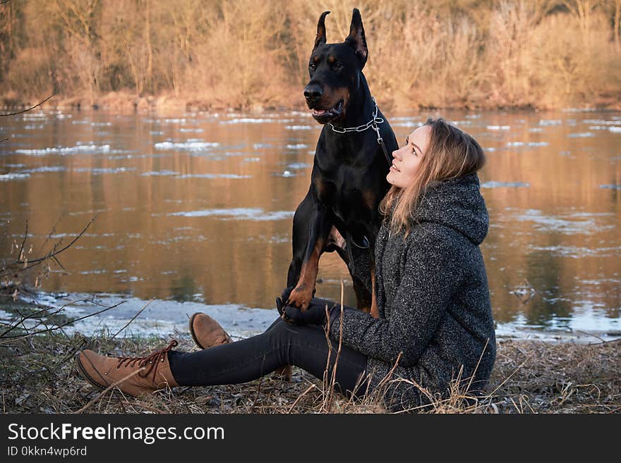 Portrait of beautiful young woman with her doberman dog. Warm natural color.