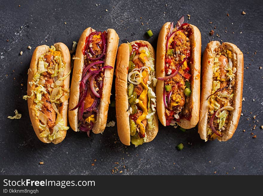 Hot dogs with a sausage on a fresh rolls garnished with mustard and ketchup and served with different toppings. Hot dogs with a sausage on a fresh rolls garnished with mustard and ketchup and served with different toppings.