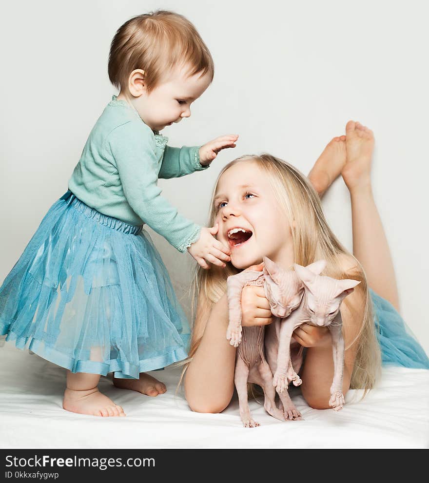 Cute baby and little girl playing with cats