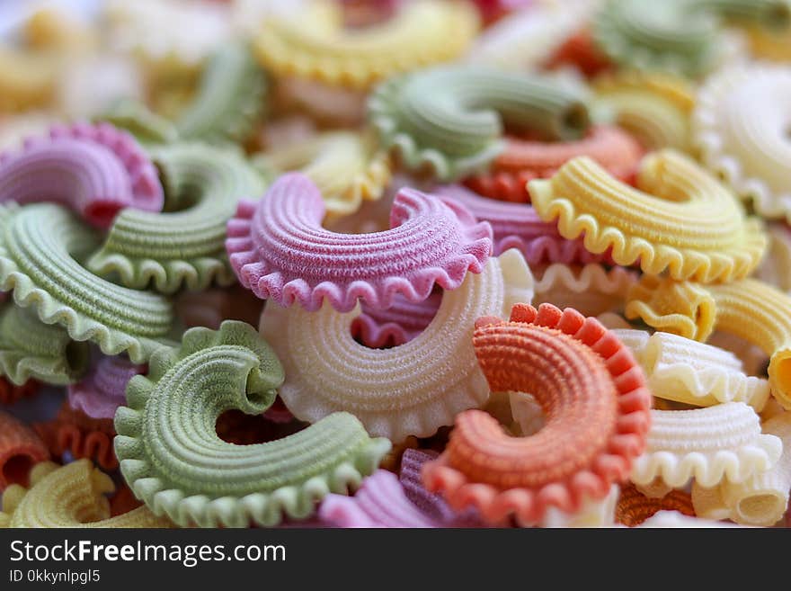 Background of colorful green, yellow, white, orange and pink italian crown pasta as creative food texture, close-up. Multicolor pasta texture pattern. Front focus