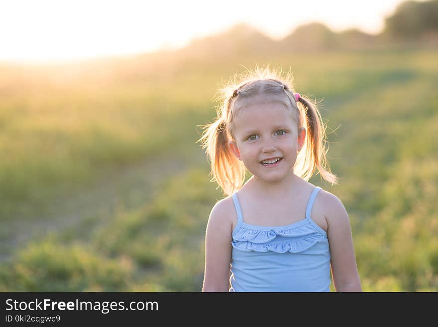 The girl is three years old, child on the field at sunset