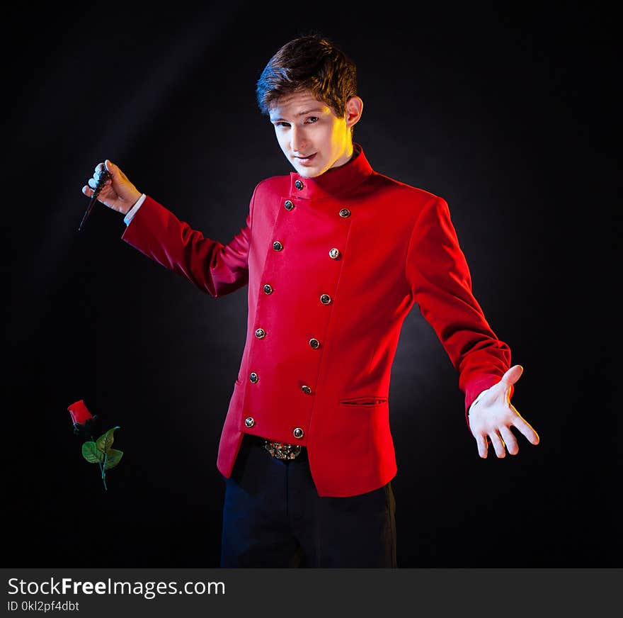 Young man in elegant red jacket showing hocus-pocus with red rose looking at camera. Young man in elegant red jacket showing hocus-pocus with red rose looking at camera.