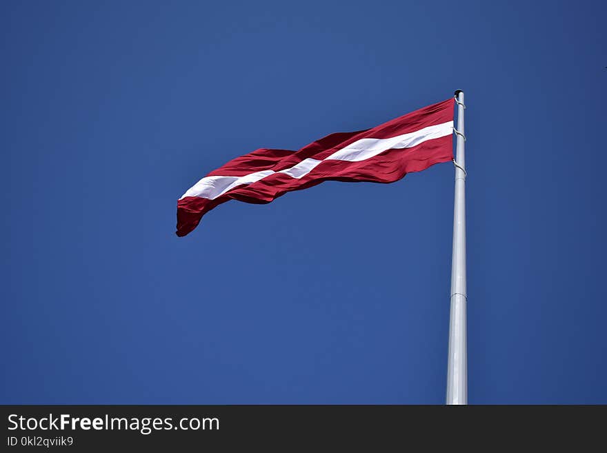 Red and White State Flag Waving Under Blue Sky at Daytime