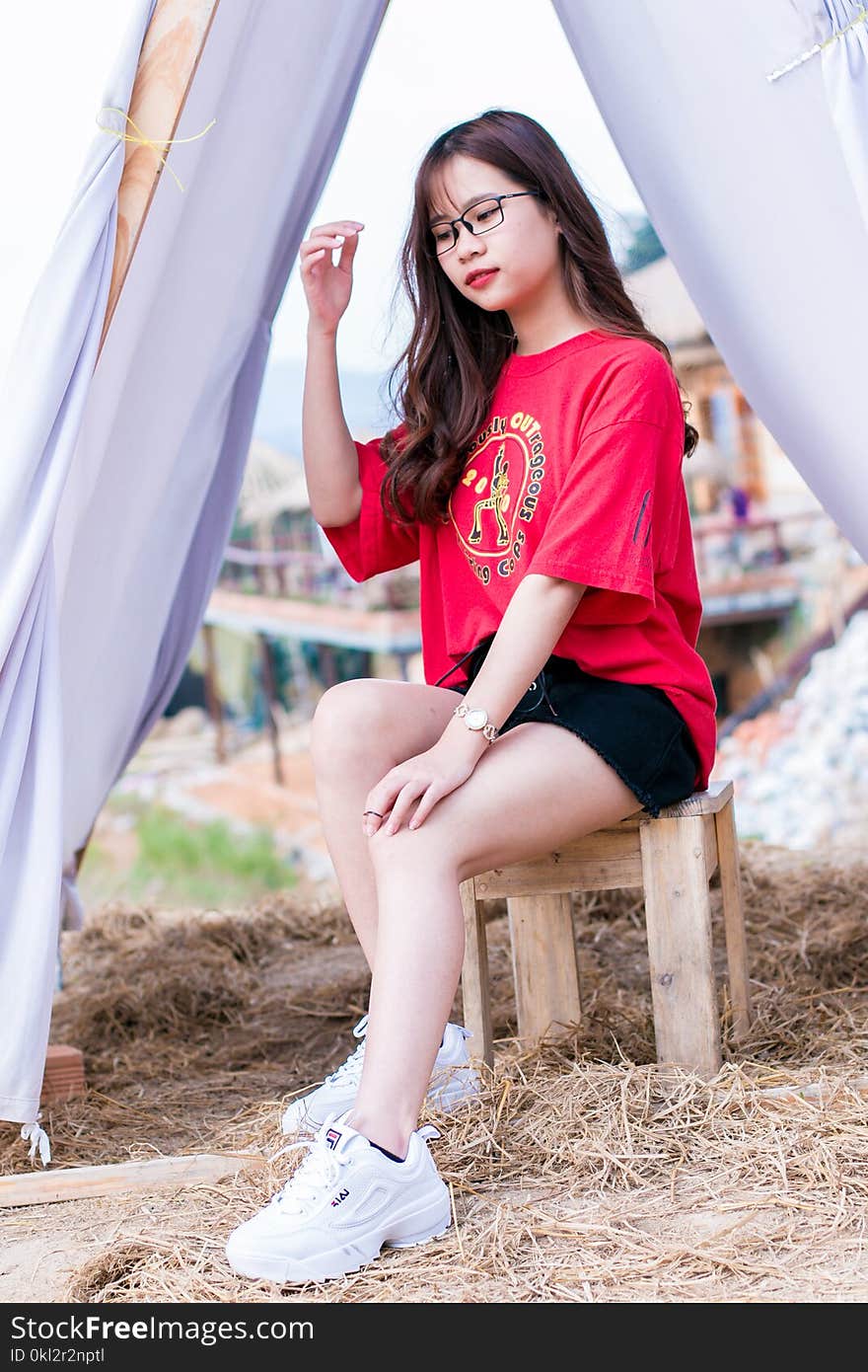 Woman Wearing Red Crew-neck Elbow-sleeved Shirt Sitting on Brown Wooden Stool