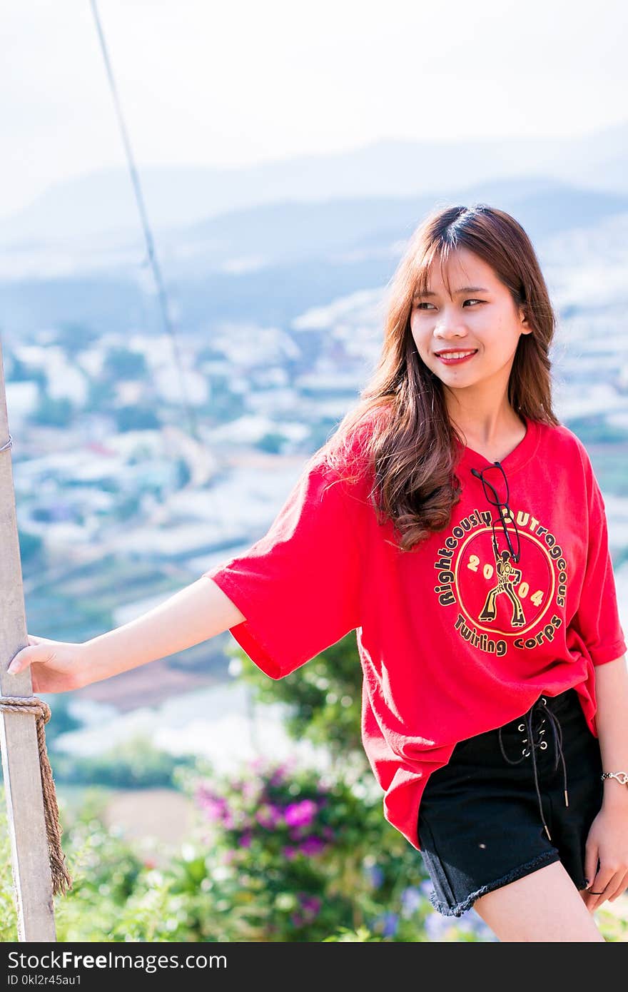 Woman Wearing Red Shirt Standing Beside a Post