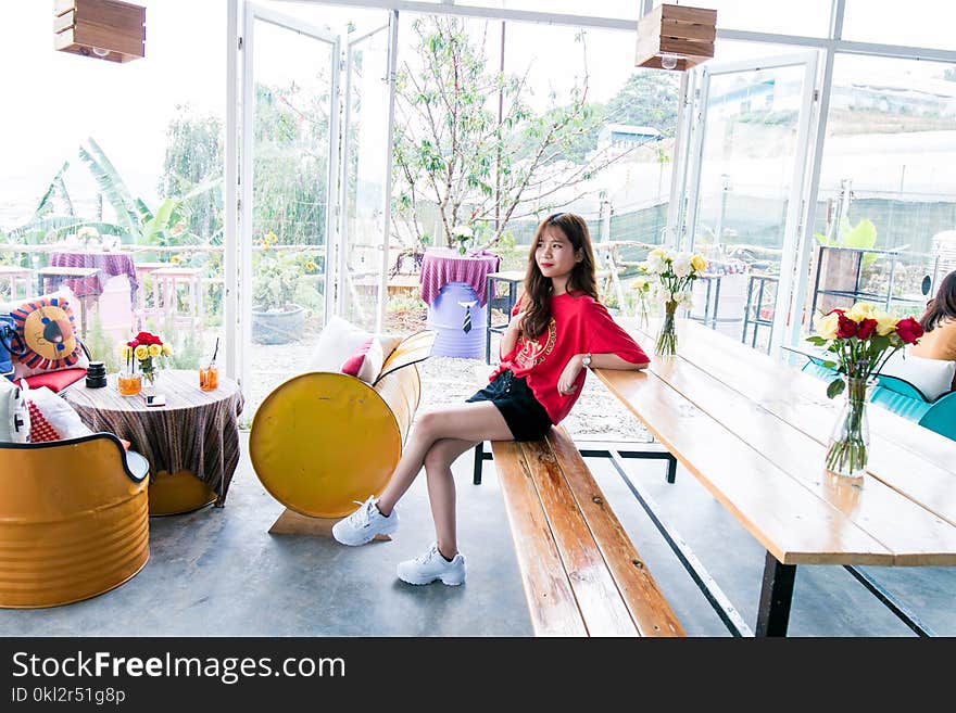 Woman in Red Crew-neck T-shirt and Blue Short Shorts Sitting on Bench