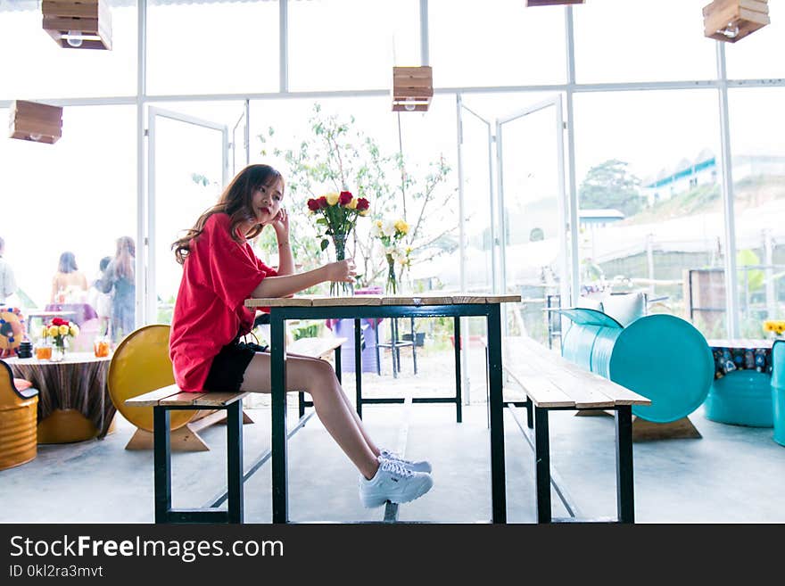 Woman Wearing Red Top Sitting in Brown Chair