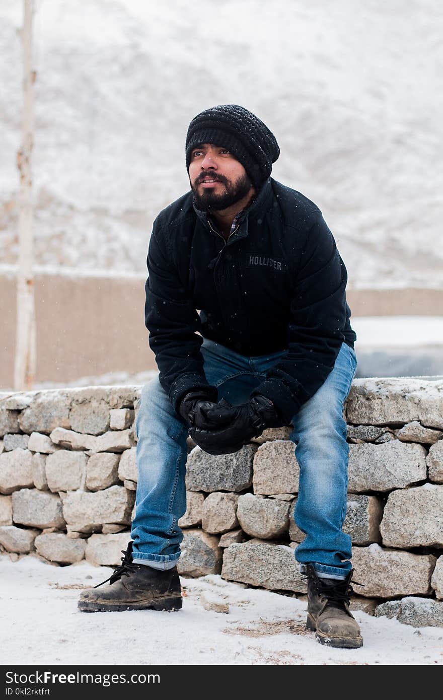 Man Sitting on Rock Wearing Black Jacket