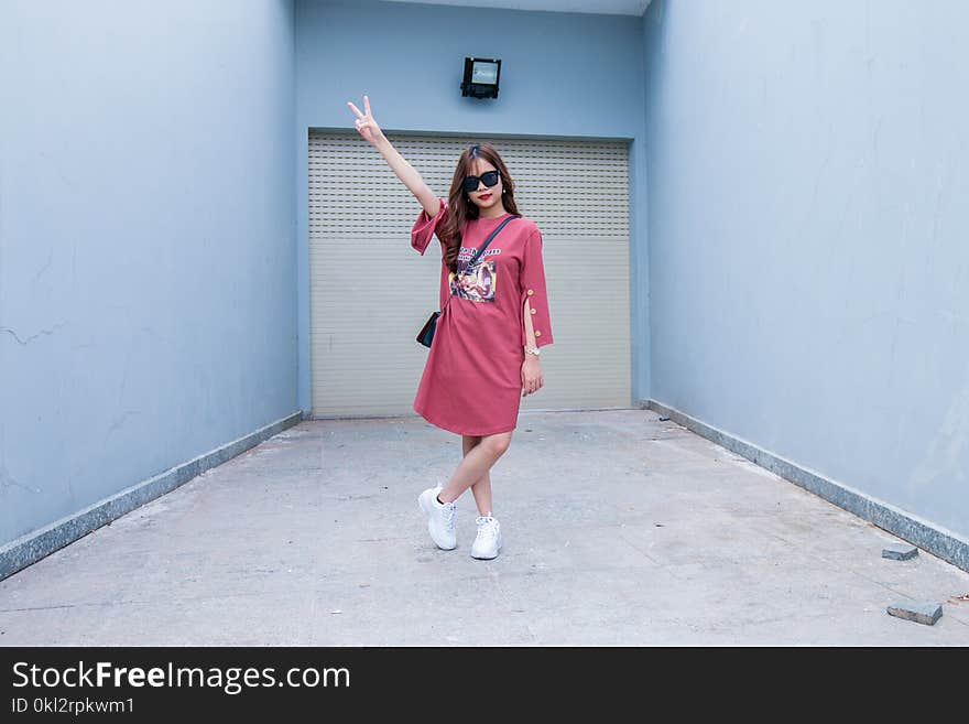 Woman Wearing Red Long-sleeved Dress Standing in Front of Shutter Door